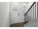Bright entryway with a white front door, hardwood floors, and a staircase with dark wood railings at 152 Global Ave, Fuquay Varina, NC 27526