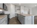 Spacious kitchen featuring gray cabinets, granite counters, a center island, and stainless steel appliances at 152 Global Ave, Fuquay Varina, NC 27526