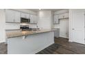 Modern kitchen with gray cabinets, granite countertops, stainless steel appliances, and a center island at 152 Global Ave, Fuquay Varina, NC 27526