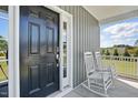 Inviting porch with rocking chairs next to a black front door with digital entry and white trim at 263 Annali Way, Wendell, NC 27591