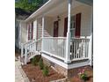 Inviting front porch with white railings and red door, complemented by a brick foundation and manicured landscaping at 334 Cabin Grove Ct, Angier, NC 27501