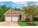 Inviting brick home showcasing a well-kept lawn, two-car garage, and tasteful light green shutters at 4 Calwell Creek Dr, Chapel Hill, NC 27517
