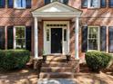Inviting front entrance with brick steps, white columns, and a classic black front door at 4533 Wood Valley Dr, Raleigh, NC 27613