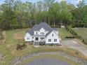Aerial view of a beautiful white home with well-kept landscaping and a circular driveway in a wooded area at 6024 Lunenburg Dr, Raleigh, NC 27603