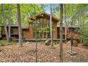 A beautiful brown home featuring a wall of windows, a wooden deck, and lush green landscaping at 673 Brookview Dr, Chapel Hill, NC 27514