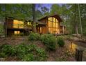 Exterior shot of a home with a wall of windows and inviting lighting as dusk settles in the surrounding landscape at 673 Brookview Dr, Chapel Hill, NC 27514
