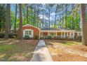 Inviting brick home featuring a lovely front porch and a neatly manicured lawn surrounded by trees at 6804 Justice Dr, Raleigh, NC 27615