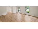 Bright living room with hardwood floors and large windows, providing ample natural light and a spacious feel at 7 Dubarry Ct, Durham, NC 27705