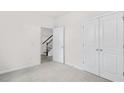 Cozy bedroom with neutral carpet, closet, and view of staircase through doorway at 764 Dorset Stream Dr, Fuquay Varina, NC 27526