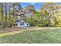 View of light blue home with a large lawn, surrounded by lush trees and a blue sky backdrop at 924 Lynn Rd, Durham, NC 27703