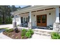 Charming front porch with stone pillars and rocking chairs, leading to a wooden double door entrance at 9947 Nc Hwy 96 N, Selma, NC 27576