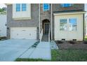 Stylish two-story home featuring a brick and stone facade, attached garage and landscaped walkway at 1004 Longleaf Pine Pl, Mebane, NC 27302