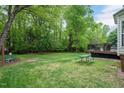 Spacious backyard featuring a picnic table, wooded area, and deck at 1027 Upchurch Farm Ln, Cary, NC 27519