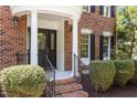 Elegant brick home featuring a covered entrance with classic columns and decorative glass front door with manicured landscaping at 103 Ticonderoga Rd, Cary, NC 27519