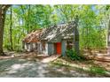 Home exterior showcasing a gray facade, orange front door with a wooden walkway, deck, and surrounded by nature at 158 Poplar St # A, Chapel Hill, NC 27516