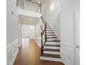 Bright entryway with wood floors, staircase with wood and white accents, and open floorplan at 317 Castle Rock Ln, Cary, NC 27519
