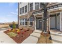 Charming townhome entrance with brick facade, stylish door, and vibrant, colorful landscaping at 404 Gaston Park Ln # 100, Wake Forest, NC 27587