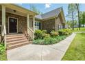 Beautiful stone house facade with brick stairs, a welcoming entrance, and lush landscaping enhancing curb appeal at 4057 Mackenzie Dr, Haw River, NC 27258