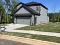 Side view of a gray home with a two-car garage, sidewalk, and grass lawn at 4404 Darius Ct # 41, Fuquay Varina, NC 27526