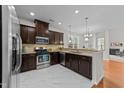 Modern kitchen featuring dark wood cabinets, granite countertops, stainless steel appliances, and marble flooring at 5518 Jessip St, Morrisville, NC 27560