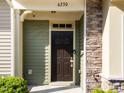 Close-up of home's front door showing dark wood finish, stone accents, and a well-kept lawn at 6230 Pesta Ct, Raleigh, NC 27612