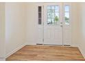 Bright foyer featuring a white door with glass panels, wood-look floors, and fresh paint at 72 S Grey Abbey Dr, Clayton, NC 27527