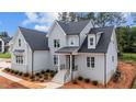 A stylish two-story home featuring light-gray brick, black accents, a manicured lawn, and an inviting entrance at 7301 Wexford Woods Ln, Wake Forest, NC 27587
