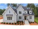 Inviting two-story home with light-gray painted brick, black accents, and manicured landscaping creates eye-catching curb appeal at 7301 Wexford Woods Ln, Wake Forest, NC 27587