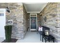 Charming covered entryway with a welcoming wreath, stone detailing, and a cozy bench at 769 Ashley Woods Dr, Gibsonville, NC 27249