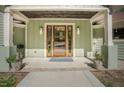 Welcoming front entryway featuring a wooden door with sidelights, elegant lighting, and a covered porch at 7955 Midnight Ln, Wake Forest, NC 27587