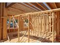 View of house framing shows interior wood beams and window placements in this new home construction at 7961 Wexford Waters Ln, Wake Forest, NC 27587