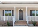Front porch with classic design elements, including white columns and a gray front door at 9391 Turkey Way, Middlesex, NC 27557