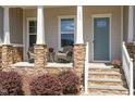 Inviting front porch with stone accents, comfortable seating, and a decorative front door at 101 Becklow Ridge Lane Ln, Holly Springs, NC 27540