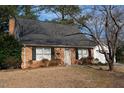Brick home with black shutters, a gray roof, and a detached white garage at 1408 Edgebrook Dr, Garner, NC 27529