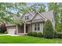 Charming home featuring a stone facade, gray siding, a well-manicured lawn, and an attached two-car garage at 144 Cobble Ridge Dr, Pittsboro, NC 27312