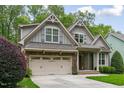 Charming home featuring a stone facade, gray siding, a well-manicured lawn, and an attached two-car garage at 144 Cobble Ridge Dr, Pittsboro, NC 27312