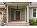 Home's cozy front porch with brick accents, decorative columns, and a beautiful wood front door with glass detailing at 144 Cobble Ridge Dr, Pittsboro, NC 27312
