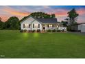 Beautiful single Gathering home on a large lot with mature trees and landscaping at sunset at 175 Bill Avery Rd, Coats, NC 27521
