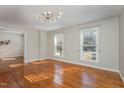Bright living room featuring hardwood floors, two large windows, and modern light fixture at 2009 Mallard Ln, Raleigh, NC 27609