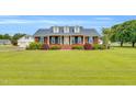 Beautiful brick home with manicured lawn, dormer windows, blue shutters, and side-entry garage at 201 Wendy Pl, Benson, NC 27504