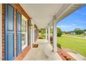 Inviting covered porch with brick accents, white columns, and a view of the lush green lawn at 201 Wendy Pl, Benson, NC 27504