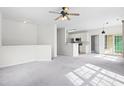 Open-concept living area with plush carpeting, ceiling fan, and a bar overlooking the modern kitchen at 2421 Kudrow Ln, Morrisville, NC 27560