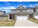 Charming two-story home with a brick and gray siding facade, well-manicured lawn, and attached two-car garage at 2528 Forge Village Way, Apex, NC 27523