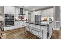 Modern white kitchen with stainless steel appliances, black countertops, and a kitchen island with clear stools at 2528 Forge Village Way, Apex, NC 27523