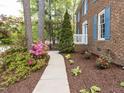 Paver walkway leads to a charming brick home with lush landscaping and a garden at 301 Trappers Sack Rd, Cary, NC 27513