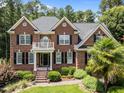 Close-up of a beautiful brick home featuring a small balcony and manicured landscaping at 5016 Dillswood Ln, Raleigh, NC 27606