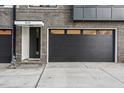 Modern townhome exterior featuring a black garage door, gray brick, and stylish entry door for a contemporary appeal at 517 Edgecreek Ct, Raleigh, NC 27604