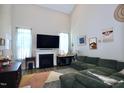 Spacious living room with high ceilings, a cozy fireplace, large TV and ample seating on a large green couch at 547 Historic Dr, Hillsborough, NC 27278