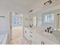 Bright bathroom with dual sinks, marble floors, white cabinets, and black hardware fixtures at 5491 Silk Hope Gum Springs Rd, Siler City, NC 27344