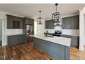 Modern kitchen featuring gray cabinets, stainless steel appliances, quartz countertops, and wooden flooring at 5491 Silk Hope Gum Springs Rd, Siler City, NC 27344